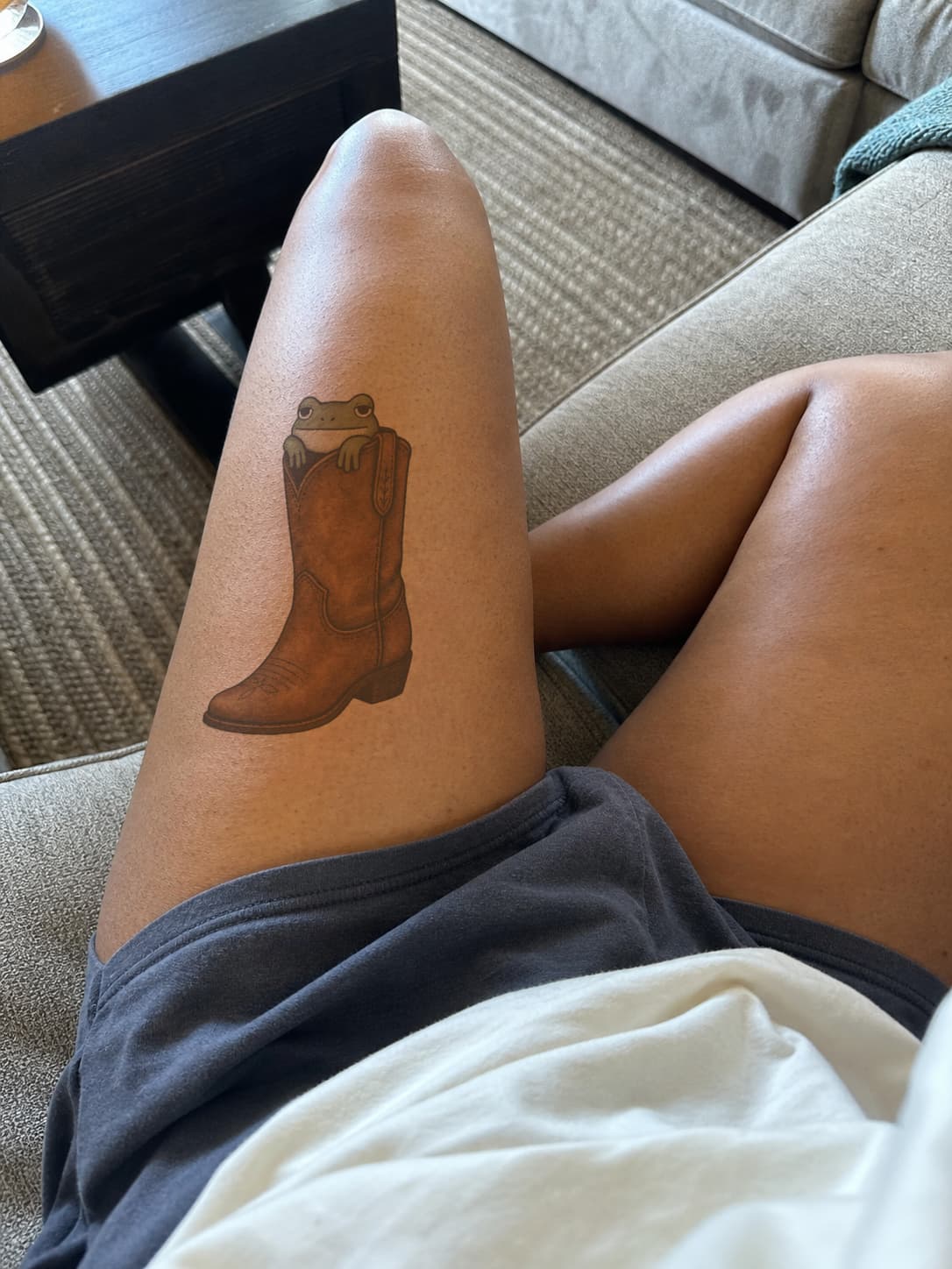 New school cowboy boot and frog previewed across a thigh in low indoor light