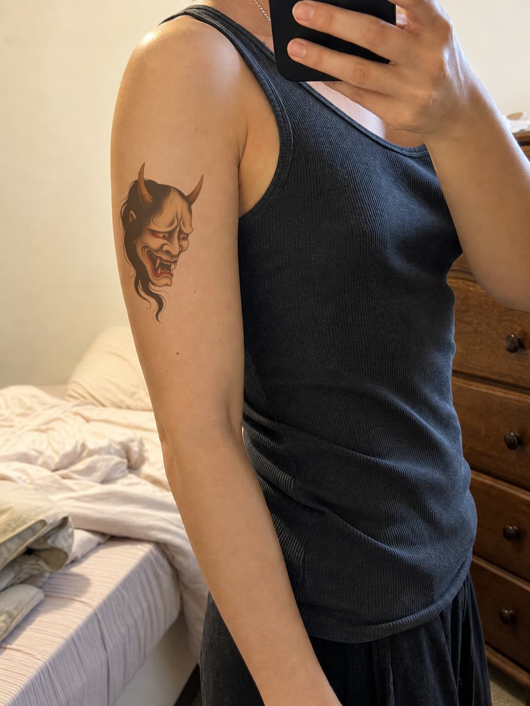Hannya mask tattoo preview following the curve of an upper arm, shown healed